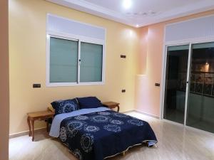 Schlafzimmer mit einem Bett und einem Fenster in der Unterkunft Appart el bassatine pr famille in Meknès