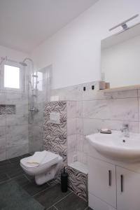 a white bathroom with a toilet and a sink at Apartmani NAN in Visoko