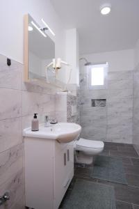 a white bathroom with a sink and a toilet at Apartmani NAN in Visoko