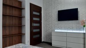 a bedroom with a tv on a wall with a dresser at Willa Piasutno z klimatyzacją in Świętajno