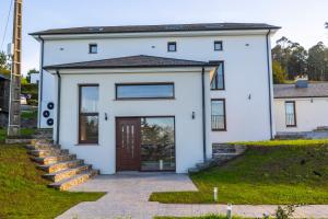 ein weißes Haus mit einer Haustür und einer Treppe in der Unterkunft Apartamentos Casona del Campo in Navia