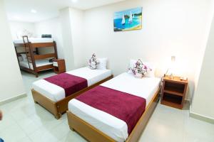a bedroom with two beds and a chair at hotel sierra nevada centro histórico in Santa Marta