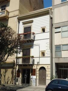 un edificio blanco con balcones y un coche aparcado delante en La Terrazza sul Massimo, en Palermo