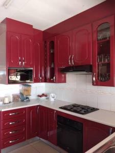 a red kitchen with red cabinets and a stove at Antique Home BnB in Gaborone