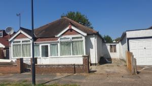 a brick house with a white garage door at Guess bungalow wembley in London