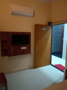 a room with a bed with a door and a television at Hotel Greenoz in Jaipur
