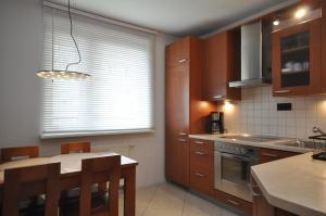a kitchen with wooden cabinets and a kitchen island with a table at Aquapark with private garage by JoApart in Krakow