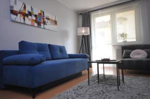 a blue couch in a living room with a table at Aquapark with private garage by JoApart in Kraków
