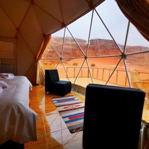 um quarto com uma cama e uma televisão numa tenda em orbit camp 2 em Wadi Rum