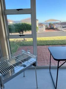 a grill in front of a window with a table at Hermanus Sea Breeze in Hermanus