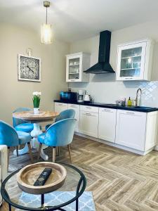 a kitchen with white cabinets and a table and chairs at Apartamenty Kamienica Arte 1 in Ustka