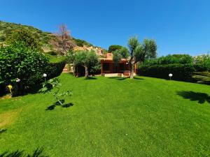 a green yard with a house in the background at Villa ValePina in Villasimius