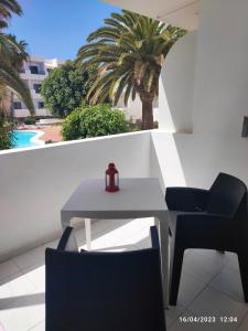 einen Tisch und Stühle auf einem Balkon mit einer Palme in der Unterkunft Precioso y céntrico apartamento in Costa Teguise