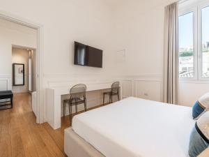 a white bedroom with a bed and a tv on a wall at PLEY Boutique Del Centro in Cagliari