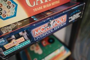 uma pilha de jogos de tabuleiro monopolistas numa prateleira em Orange Rentals - In my 4 bedroom Liverpool Home em Liverpool