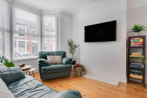 a living room with a couch and a television on a wall at Orange Rentals - In my 4 bedroom Liverpool Home in Liverpool