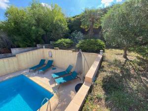basen z krzesłami i parasolem obok niego w obiekcie Maison de famille (piscine, jacuzzi et sauna) w mieście Quillan