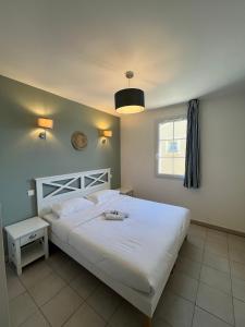 Un dormitorio con una gran cama blanca y una ventana en Les Maisons du Golf de la Cabre d'Or by Ateya Vacances, en Cabriès