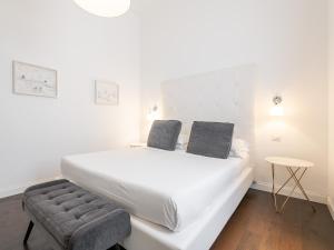 a white bed with two pillows and a chair in a room at PLEY Cagliari Boutique Suites in Cagliari