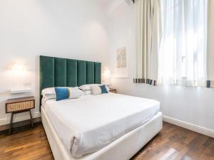 a bedroom with a large white bed with a green headboard at PLEY Cagliari Boutique Suites in Cagliari