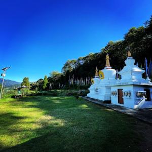 ein kleiner weißer Tempel auf einem Grasfeld in der Unterkunft Lali Gurash Homestay - Okhrey in Sombāri