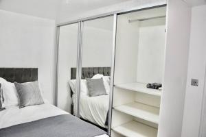 a white bedroom with a mirror and a bed at The White House Retreat in London