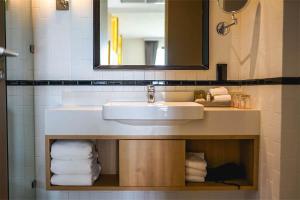 a bathroom with a sink and a mirror and towels at Brique Suite in Chiang Mai