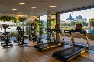 - une salle de sport avec des appareils de cardio-training et une grande fenêtre dans l'établissement Brique Suite, à Chiang Mai