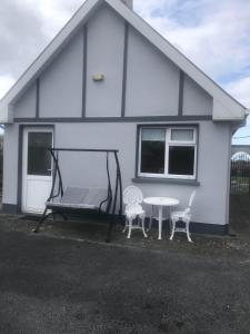 a house with a swing and a table and two chairs at Riverside in Doonbeg