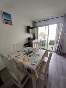 - une table à manger avec des chaises et une couette dans l'établissement Résidence "Les balcons de la mer", à Marseillan