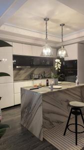 uma cozinha com armários brancos e uma ilha de cozinha com um banco em Casa in inima capitalei em Bucareste