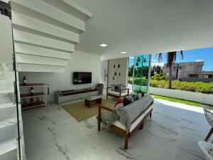 a living room with a couch and a tv at Casa Maragogi, Piscina, 4 Suítes, 100 Mts Praia in Maragogi