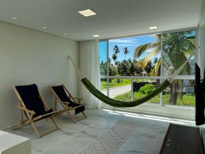 a room with two chairs and a hammock in front of a window at Casa Maragogi, Piscina, 4 Suítes, 100 Mts Praia in Maragogi