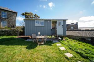 a tiny house with a table and chairs in a yard at The Shepherd's Hut in Penzance