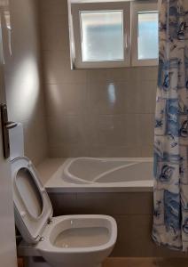 La salle de bains est pourvue de toilettes et d'une baignoire. dans l'établissement Villa Wind Apartments, à Drače