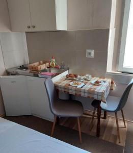 une petite cuisine avec une table et deux chaises dans l'établissement Villa Wind Apartments, à Drače