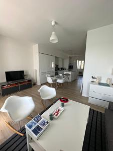 salon ze stołem i białymi krzesłami w obiekcie Appartement Design I - Port du Rosmeur - Douarnenez w mieście Douarnenez