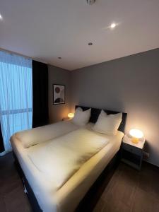 ein großes weißes Bett in einem Zimmer mit zwei Lampen in der Unterkunft mala me Hotel in Hannover