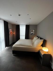 1 dormitorio con 1 cama grande con sábanas y almohadas blancas en mala me Hotel, en Hannover