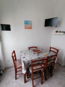 a dining room table with four chairs and a television at Casa sul mare in Procida