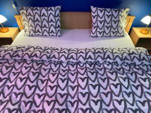 a bed with a purple comforter and two pillows at Remo's Villa by Zugló in Budapest