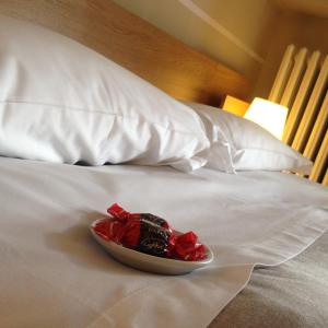 a plate of red flowers on a white bed at B&B Casa Bona in Alba