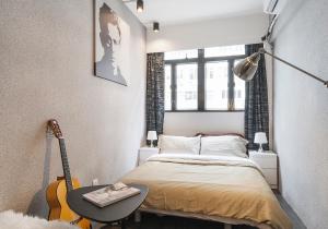 een kleine slaapkamer met een bed en een gitaar bij Athena in Hong Kong