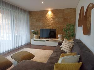 uma sala de estar com um sofá e uma televisão em L Orangerie CA by Intiholidays em Vilamoura