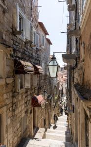 Une allée avec des bâtiments et des parasols et une personne qui la descend dans l'établissement Central Old Town Apartments, à Dubrovnik