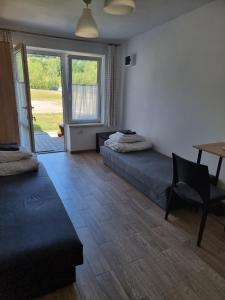 a room with two beds and a table and a desk at Słoneczna Przystań Klimkówka pokoje camp pole namiotowe in Klimkówka