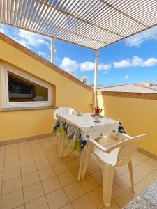 eine Terrasse mit einem Tisch und Stühlen an einer gelben Wand in der Unterkunft Casa Vacanze Cau in Alghero