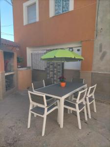 una mesa con 4 sillas y una sombrilla verde en Casa joselito, en Casas del Cerro