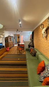 ein Wohnzimmer mit einem grünen Sofa und einer Ziegelwand in der Unterkunft Casa charmosa chác Santo Antônio in São Paulo