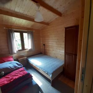 1 dormitorio con 1 cama en una cabaña de madera en ZDORKOWO, en Harsz